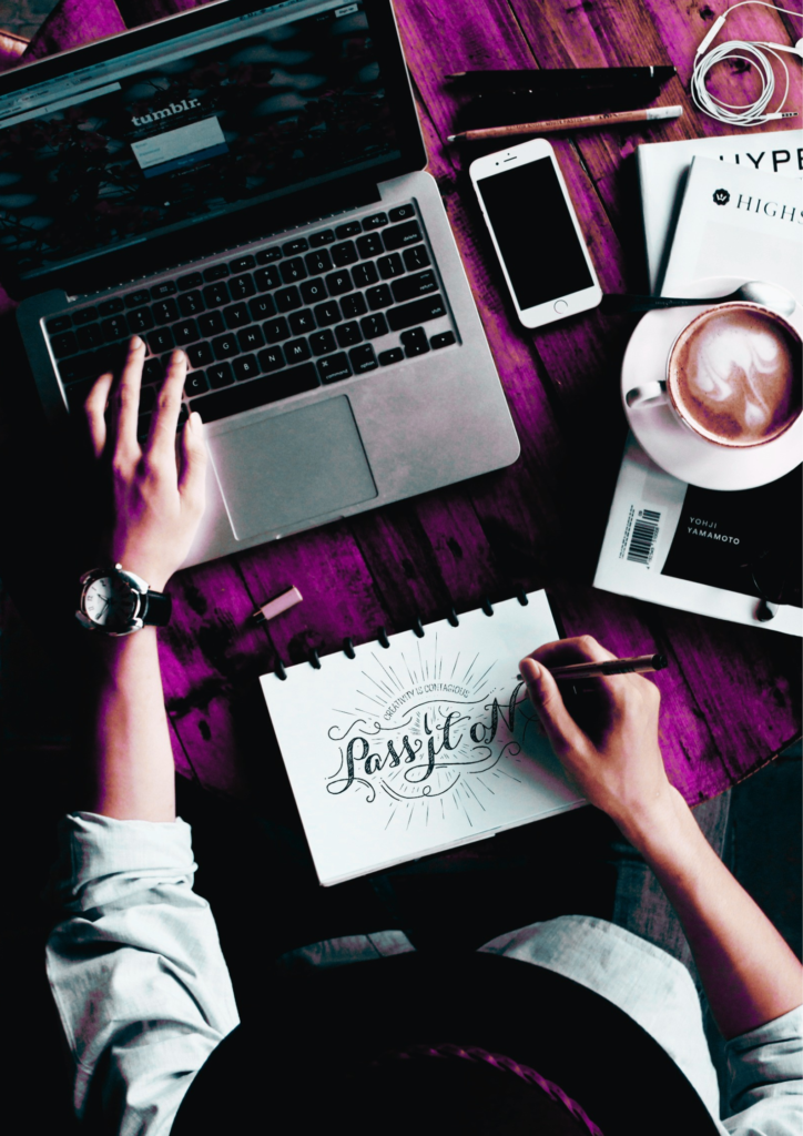 an aerial view of a graphic designer sketching a design with a laptop, mobile and coffee